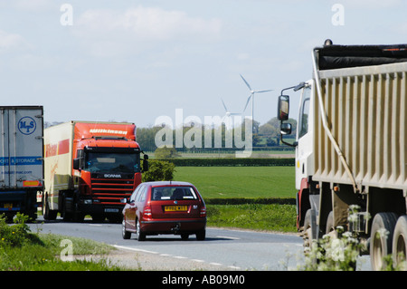 Schwerlastverkehr auf der belebten A47 in Swaffham Norfolk vor dem Hintergrund der landwirtschaftlichen Landschaft und Windturbinen. Stockfoto