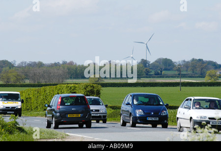 Verkehr auf der belebten A47 in Swaffham Norfolk vor dem Hintergrund der landwirtschaftlichen Landschaft und Windturbinen. Stockfoto