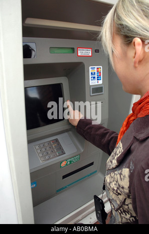 Junge Frau, die Geld von Geldautomaten Stockfoto