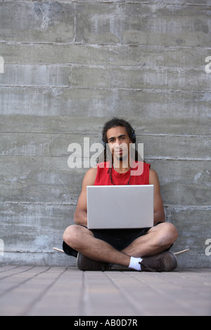 Junger Mann mit Dreadlocks mit einem Laptopcomputer Stockfoto