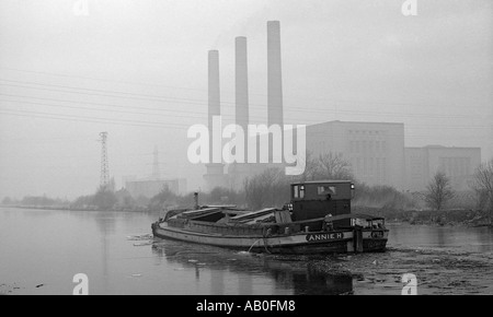 Binnenschiff Fahrt entlang Kanal im Winter mit Kohle befeuert Kraftwerk im Hintergrund. Stockfoto