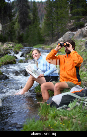 Rucksackreisen paar setzen Sie sich an einem Bach auf Karte ansehen Stockfoto