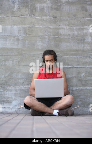 Junger Mann mit Dreadlocks mit einem Laptopcomputer Stockfoto