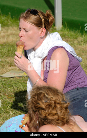 Junge Frauen genießen Eis sitzen auf dem Rasen an einem sonnigen Tag bei Hay Festival Hay on Wye Powys Wales UK Stockfoto