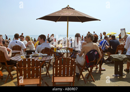 Genießen einen Drink in der Strandbar auf einem belebten heißen Sommertag bei Brighton UK Stockfoto