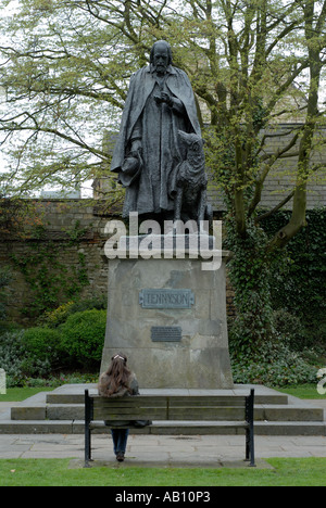 Eine Frau sitzt auf einem Park Bench Comtemplating eine Statue von Alfred Lord Tennyson Tennison in Lincoln Kathedrale Stockfoto