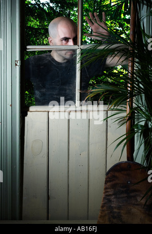 Finsteren Charakter durch ein zerbrochenes Fenster Stockfoto