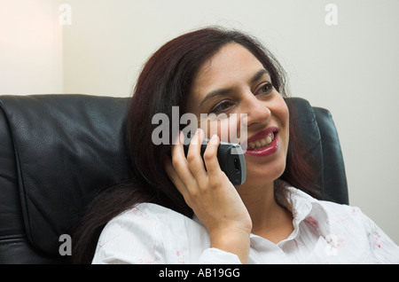 Junge Frau sitzt in ein Bürosessel mit einem schnurlosen Telefon Stockfoto