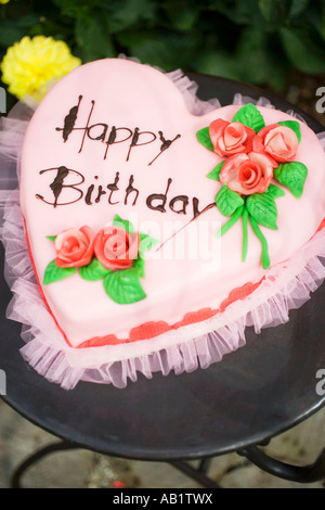 Rosa herzförmige Geburtstagstorte auf Gartentisch FoodCollection Stockfoto