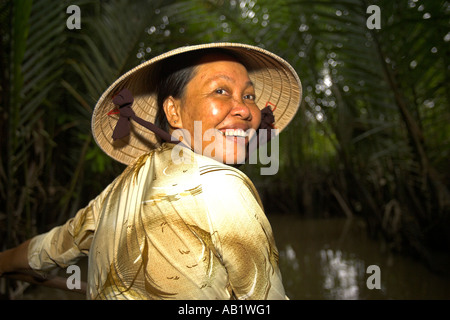 Frau in konische Hut Paddlling Boot durch die Backwaters und Palmen Vietnam Mekong Delta Stockfoto