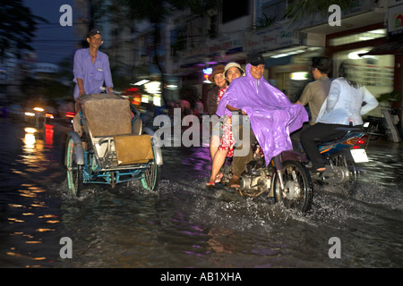 Cyclo Rikscha und Motorräder auf überfluteten De Tham Street Pham Ngu Lao Bezirk Ho Chi Minh City, Vietnam Stockfoto