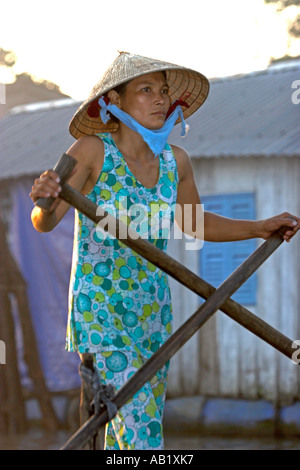 Frau in konische Hut Steh- und Paddlling Fluss Boot mit traditionellen Kreuz Ruder Bewegung Vietnam Mekong Delta Stockfoto