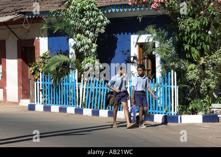 Zwei Schüler Spaziergang vorbei an leuchtend blauen Kolonialhaus in Fontainhas Bezirk von Panjim Goa Stockfoto