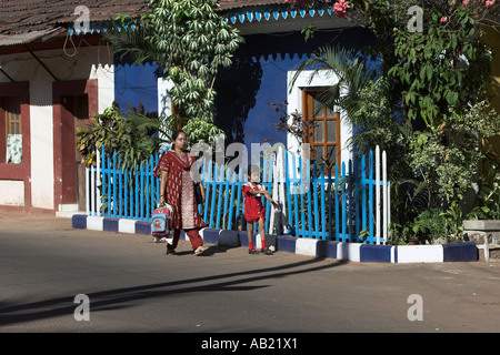 Frau im Sari und Kind gehen vorbei an leuchtend blauen Kolonialhaus in Fontainhas Bezirk von Panjim Goa Indien Stockfoto