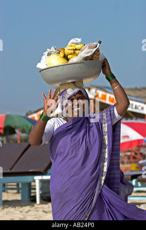 Lächelnde Frau in Sari mit Obst aus der Schüssel auf dem Kopf Cavelossim Beach Goa Indien durchgeführt Stockfoto