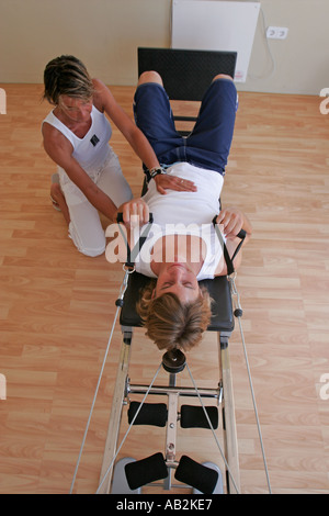 persönliche Trainer helfen Mann am Heimtrainer Stockfoto