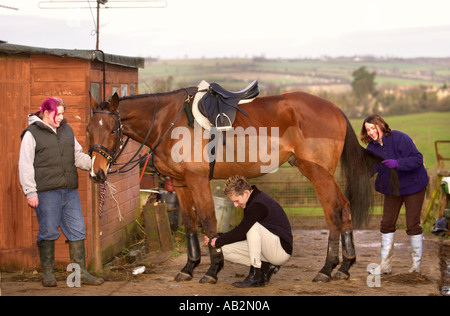 EINE GRUPPE VON JUNGEN PFERDELIEBHABER VORBEREITEN EIN PFERDES FÜR JAGD OXFORDSHIRE UK JAN 2005 Stockfoto