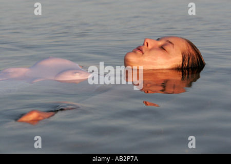 junge Frau schweben und entspannen im Wasser mit geschlossenen Augen Stockfoto