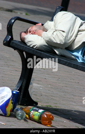 Junger Mann nach einer durchzechten Nacht, County Down, Nordirland auf Bank in der Straße in Downpatrick betrunken liegend Stockfoto