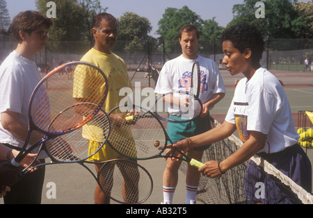 Ein Tennislehrer wird erläutert, wie einen Tennisschläger Nutzungszeit eine Tennis-Stunde für Erwachsene, Clissold Park, Stoke Newington, London, UK Stockfoto