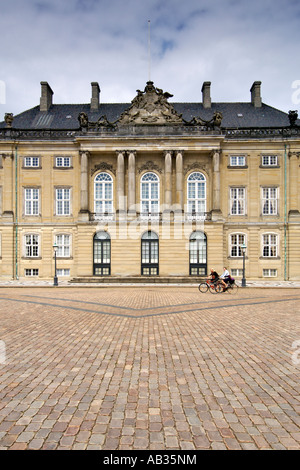 Zwei Frauen Radfahren vorbei an Christian VIII Palast, auch bekannt als die Levetzau, auf Amalienborg in Kopenhagen. Stockfoto