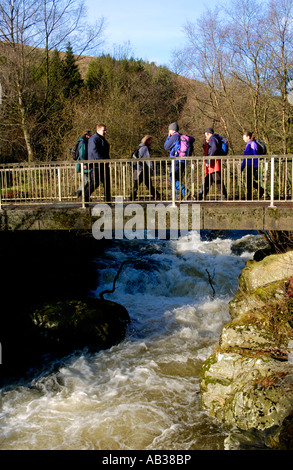 Wanderer, die Teilnahme an Real Ale Wanderung walking Festival überqueren die schnell Irfon der Flowimg River in der Nähe von Llanwrtyd Wells Powys Mid Wales Stockfoto