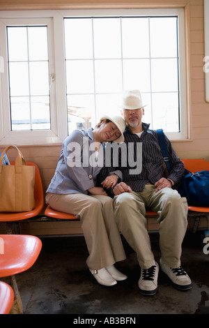 Älteres Paar, schlafen, sitzen auf der Bank am Bahnhof Stockfoto