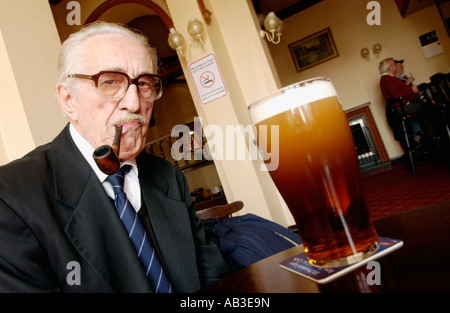 Älterer Mann Saugen an seinem unbeleuchteten Rohr wegen Rauchen in Kneipe Crumlin South Wales UK Stockfoto