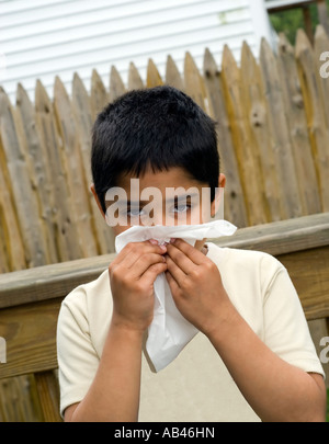 Ein hübscher Junge mit einem Taschentuch an seiner Nase Krankenschwestern eine Erkältung Stockfoto
