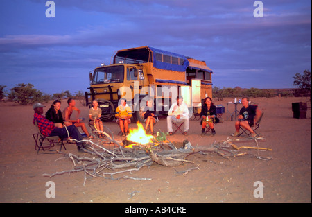 Touristen sitzen um ein Feuer auf einem Campingplatz Bush auf eine Überlandreise in der namibischen Wüste. Stockfoto