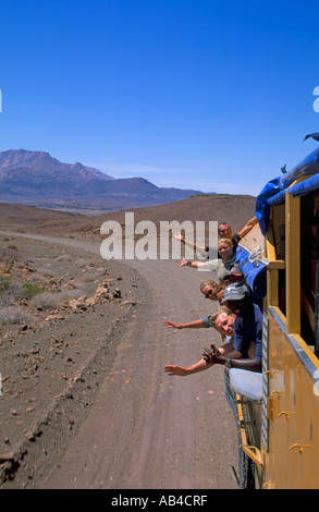 Passagiere auf eine Überlandreise vom LKW auf einer abgelegenen Wüste Straße winken. Stockfoto