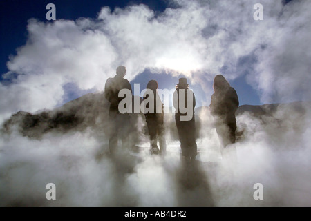 Vier Touristen Silhouette unter Dampf aus bei El Tatio Geysire in der frühen Morgensonne. Stockfoto