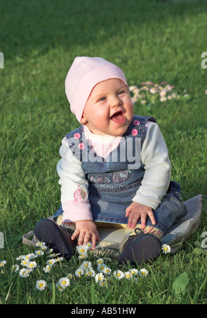 Lächelndes Babymädchen 7 Monate sitzen auf Rasen Stockfoto