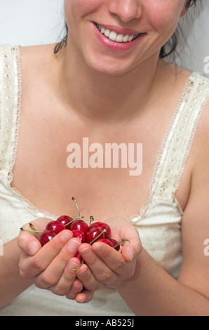Lächelnde junge Frau hält, dass Kirschen hautnah Stockfoto