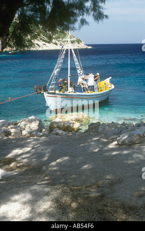 Fischer ausbessern Netze in einem Fischerboot vor Anker bei Agios Nikolaos im Nordosten der griechischen Insel Zakynthos, Griechenland Stockfoto