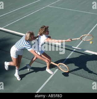 junger Mann und Frau jagt Ball auf Tennisplatz Stockfoto
