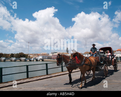 Pferd und Fahrt mit der Kutsche über den Fluss Rio Gilao mit Ponta Romana oder Römerbrücke über Tavira-Algarve-Portugal Stockfoto