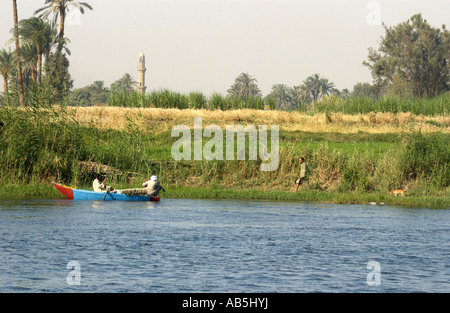 Ägyptischen Mannes Rudern an den Ufern des Flusses Nil, Ägypten mit einem Minarett im Hintergrund Stockfoto