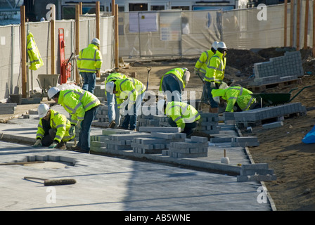Gruppe von Männern bei der Arbeit, die Bausteine mit Warnjacken und Schutzhelmen verlegen Southwark London England UK Stockfoto