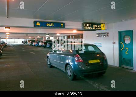 Innenansicht des besetzten PKW-Stellplätze im Stadtzentrum Parkhaus mit Autofahrer fahren entlang in Richtung Ausgang Stockfoto