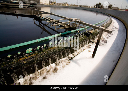 Ein rotierende Filter schöpft Schaum von der Oberfläche des Abwassers in ein Absetzbecken auf einer Kläranlage. Stockfoto