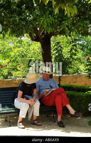 Applying paar entspannen unter einem Baum in legere Sommerkleidung und Strohhüte gekleidet. Europäer Stockfoto