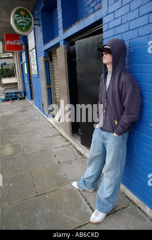 Junger Bursche mit hoody herumhängen Shops unter Wohnsiedlung. Stockfoto