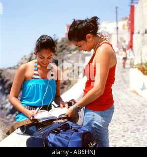 Junge Frauen Student Touristen auf einen Urlaub am Mittelmeer in Santorini Griechenland einen Reiseführer zu betrachten. Stockfoto