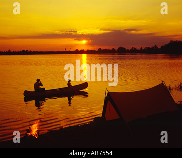 Vater und Sohn Paddel Kanu bei Sonnenuntergang in der Nähe ihres Campingplatzes Stockfoto