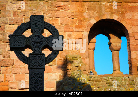 England Northumberland Lindisfarne Holy Island Celtic Stil Grabstein gegen die Ruinen des Klosters Lindisfarne Stockfoto