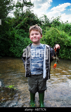 4 - Klaue 7 Jahre alter Junge stehend in Toten Flusskrebse Abhaltung von Orange suchen zufrieden mit sich selbst Stockfoto