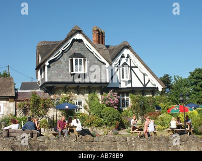 An einem sonnigen Tag am blauen Himmel sitzen Menschen im Freien und speisen im Garten mit Sonnenschirm und Sonnenschirm in einem Teestube-Geschäft in Shanklin Isle of Wight England, Großbritannien Stockfoto