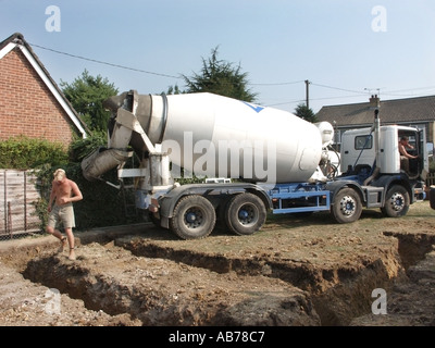 Große Lkw rückwärts auf der Baustelle zu Beton in Graben füllen Grundlagen für neue freistehendes Haus auf einem Grundstück UK gießen Start Stockfoto