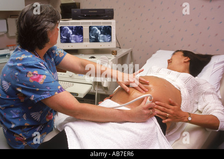 Ärztin mit Ultraschall-Test, schwangere Frau mit 5 Monate alten Fötus auf Monitor Bildschirme Stockfoto